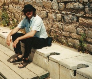 Bob Cromwell seated on the ancient public toilets in Ephesus.