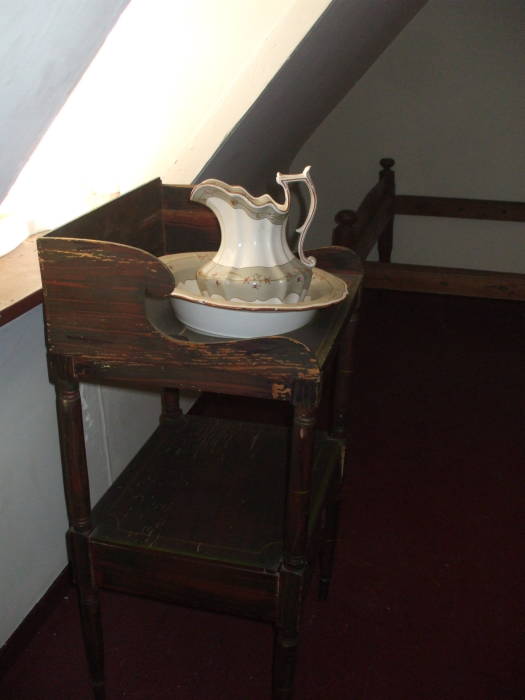 Washbasin in Edgar Allan Poe's bedroom in Baltimore.  Ceramic bowl and pitcher in a wooden stand with a large hole.