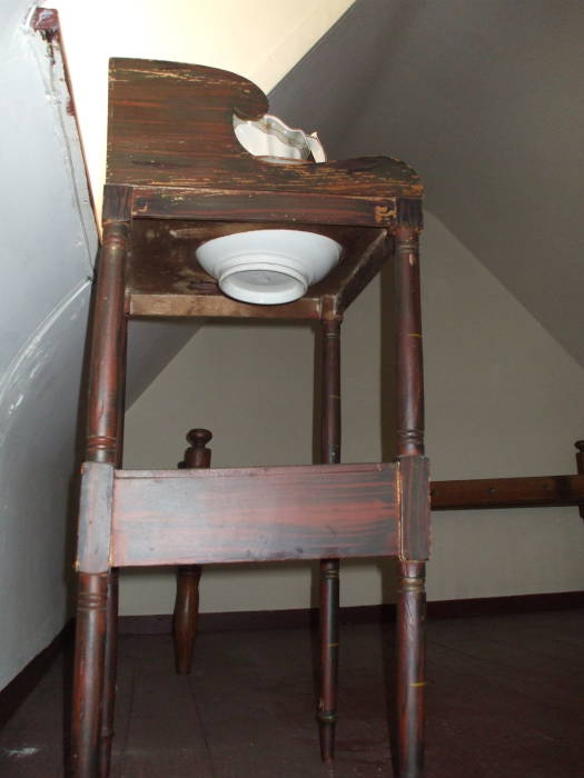 Washbasin in Edgar Allan Poe's bedroom in Baltimore.  Ceramic bowl and pitcher in a wooden stand with a large hole.