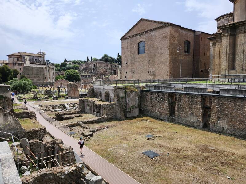 Cloaca Maxima comes into view in the Central Forum area. It runs beneath Via della Curia. Curia Iulia, Senate house from 44 BCE is on the left. Chiesa dei Santi Luca e Martina Martiri to the right.
