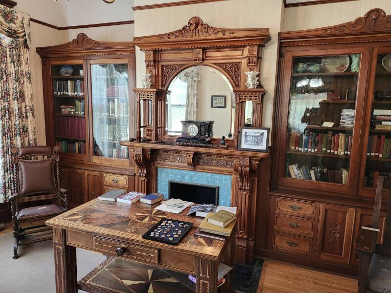 Library with marquetry table and glass-fronted book cases.