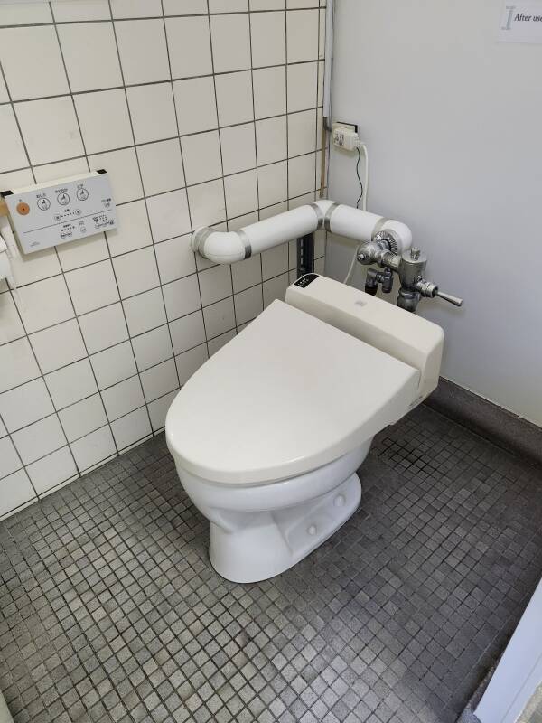 Modern toilet with control panel on the wall.