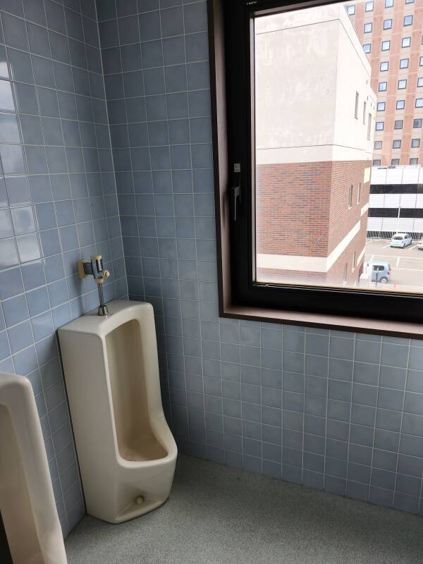 Urinals next to a large window in a hotel in Hakodate, Japan.