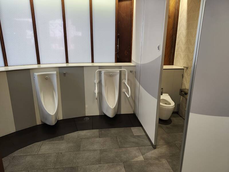 Interior of men's toilet: two urinals and a toilet.