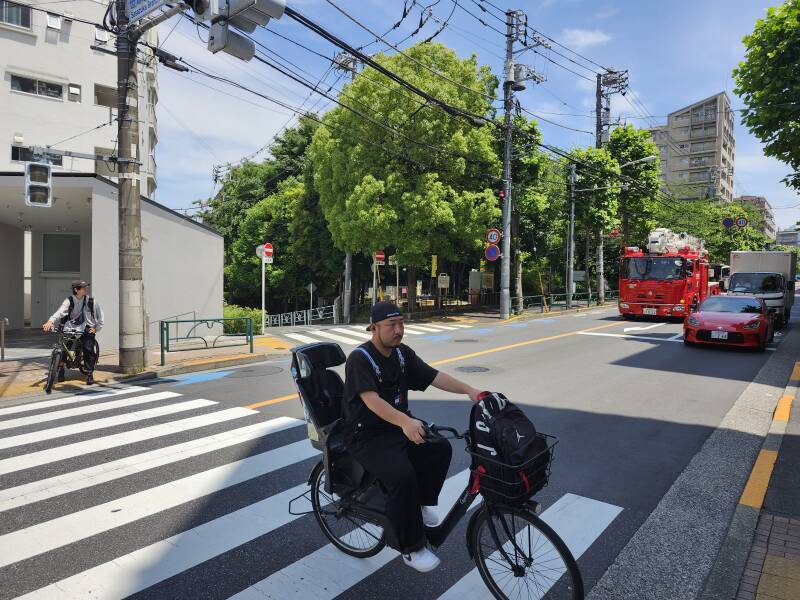 A bicyclist crosses the street as a fire truck approaches.