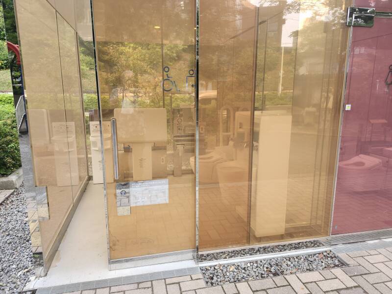 Ostomate fixture in glass toilet at Yoyogi Fukamachi park in Shibuya, Tokyo, Japan, glass powered up in translucent mode.