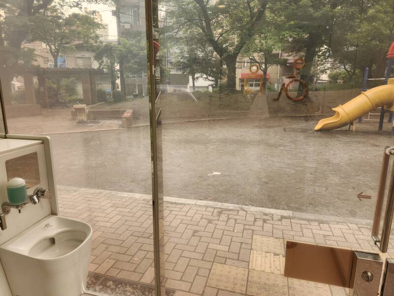 Ostomate fixture in glass toilet at Yoyogi Fukamachi park in Shibuya, Tokyo, Japan, glass powered up in translucent mode.