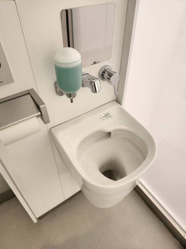 Ostomate fixture in glass toilet at Yoyogi Fukamachi park in Shibuya, Tokyo, Japan, glass unpowered with the door latched, defaults to opaque mode.