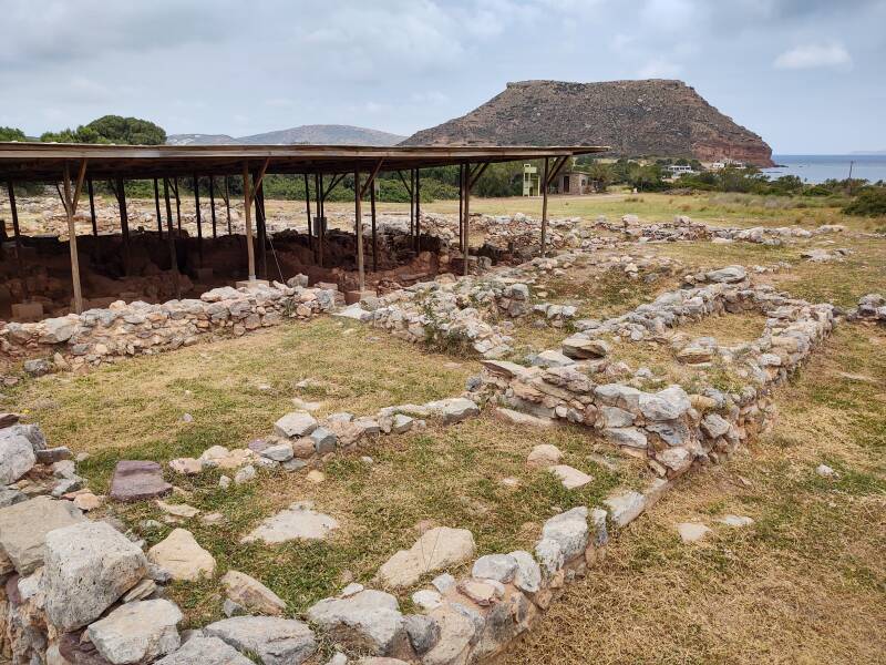 Covered mudbrick structures where the Palaikastros Kouros was found, in the Minoan port city of Roussolakkos. The rock outcropping known as Palaikastros is on the shoreline in the distance.