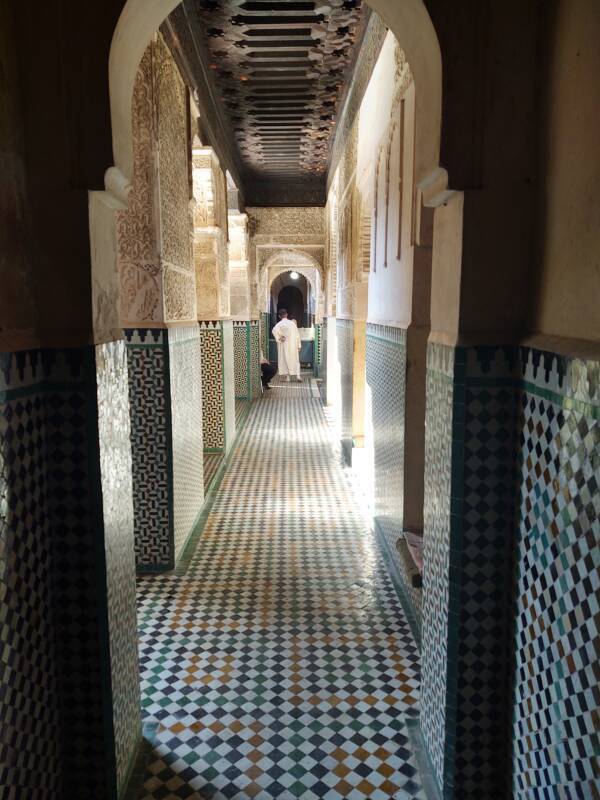 Man in a djellaba at the far end of a hallway in the Bou Inania Madrasa in Fez.