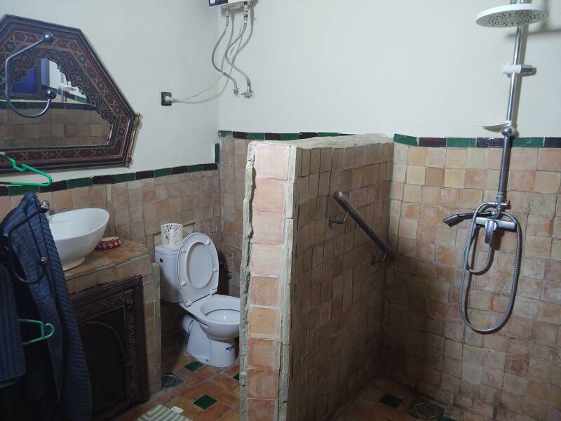 Mirror, sink, toilet, hot water heater, and shower at a riad-style guesthouse in the medina in Meknès.