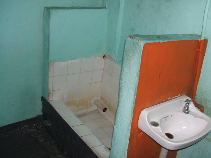 Large tile-lined trough-shaped urinal at a bar in Trinidad.