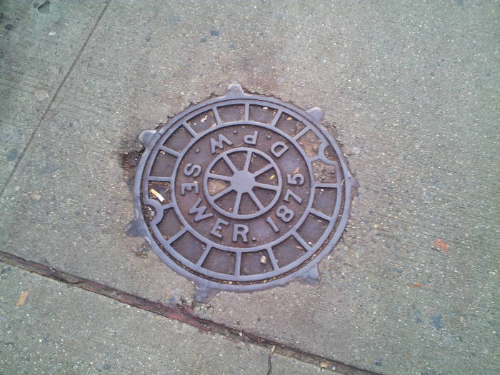Manhole cover in Manhattan: 'D.P.W. Sewer. 1875'