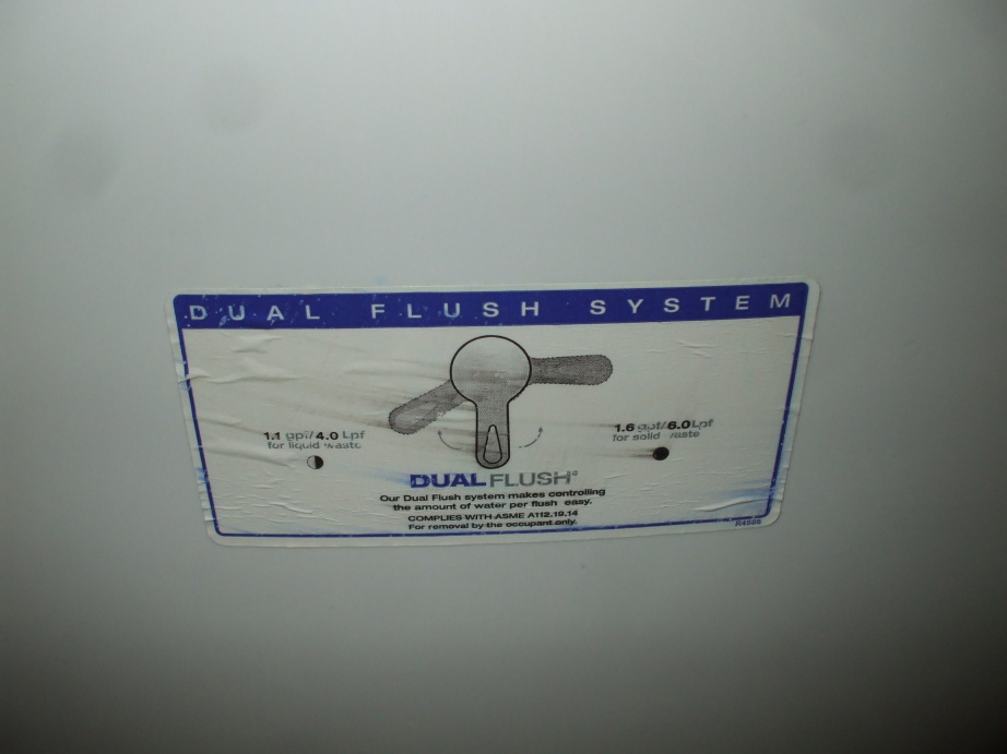 Sticker met uitleg over een dual-flush toilethendel op de tank.