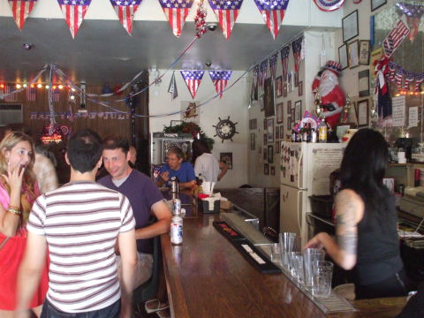Interior of Welcome To The Johnson's Bar on Rivington Street on the Lower East Side in New York: tattooed bartender, bar and patrons.