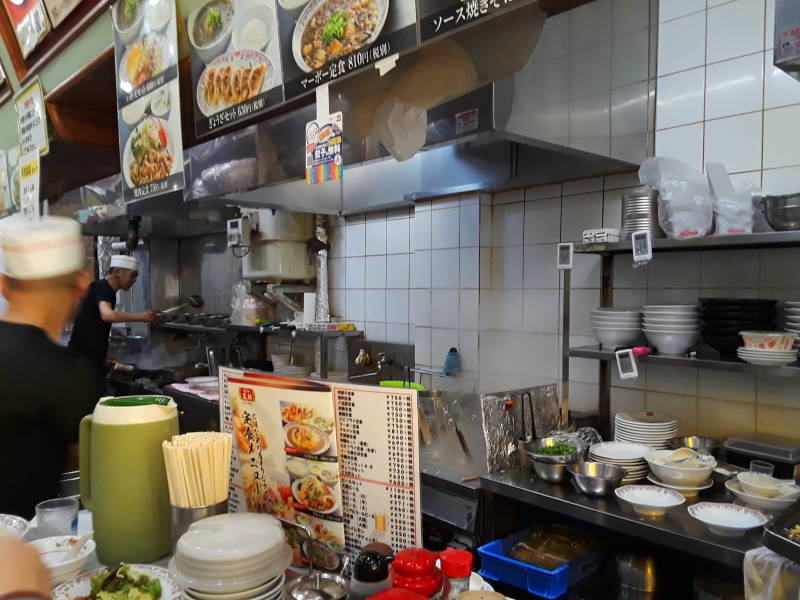 Cooks work behind the counter at a noodle shop in Osaka.