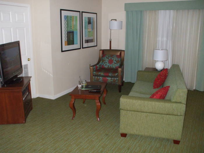 Hotel suite: television, couch, coffee table and chair.