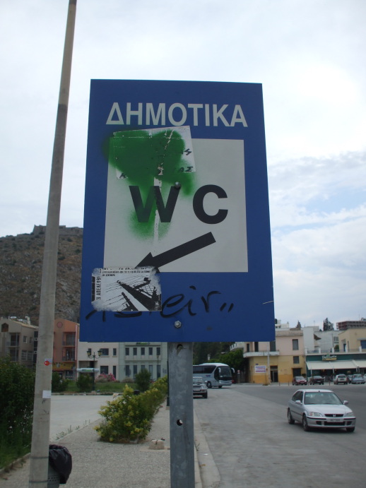 Graffiti-obscured sign to the public toilet near the train station in Nafplio, Greece.