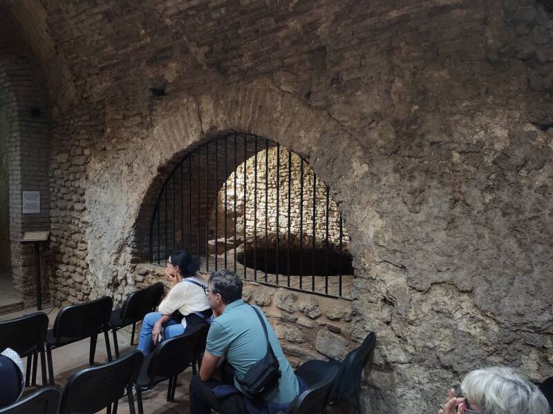 Archway into the infrastructure space with the furnace, bronze boiler, and water reservoir.